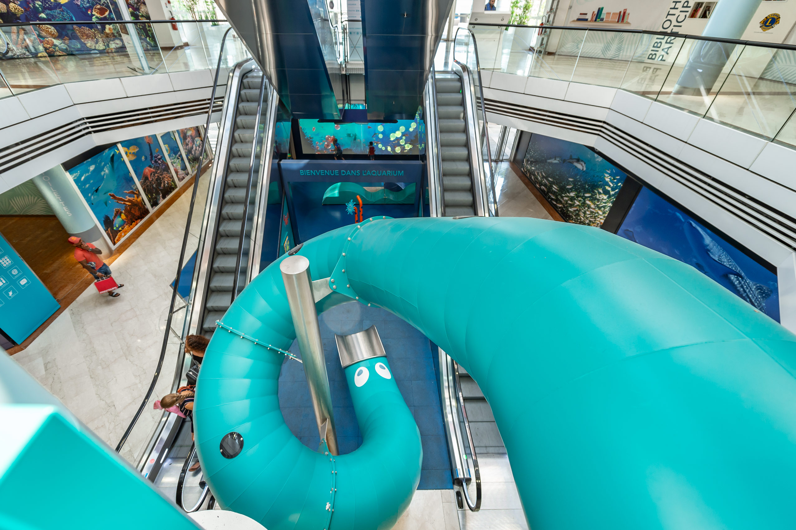 Blick von oben auf eine indoor Tunnelrutsche in türkis in einem Shoppingcenter in Frankreich