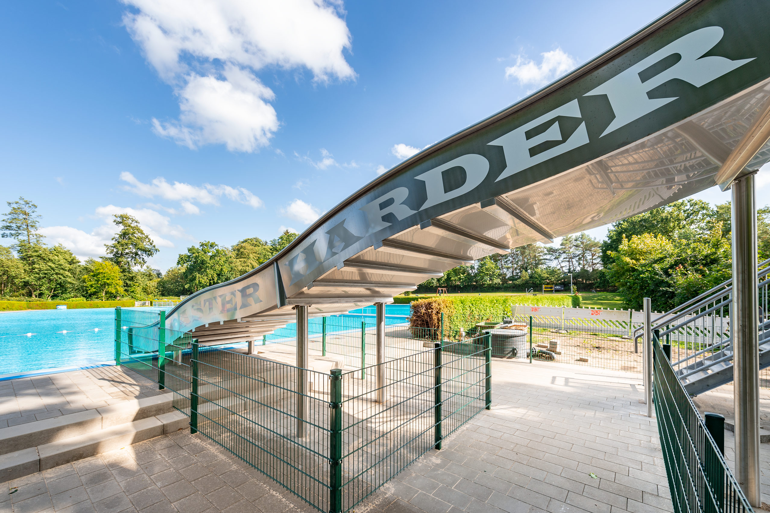 Breitwellenwasserrutsche aus Edelstahl im Freibad in Wacken, mit Aufschrift Faster Harder Louder für das Wacken Open Air