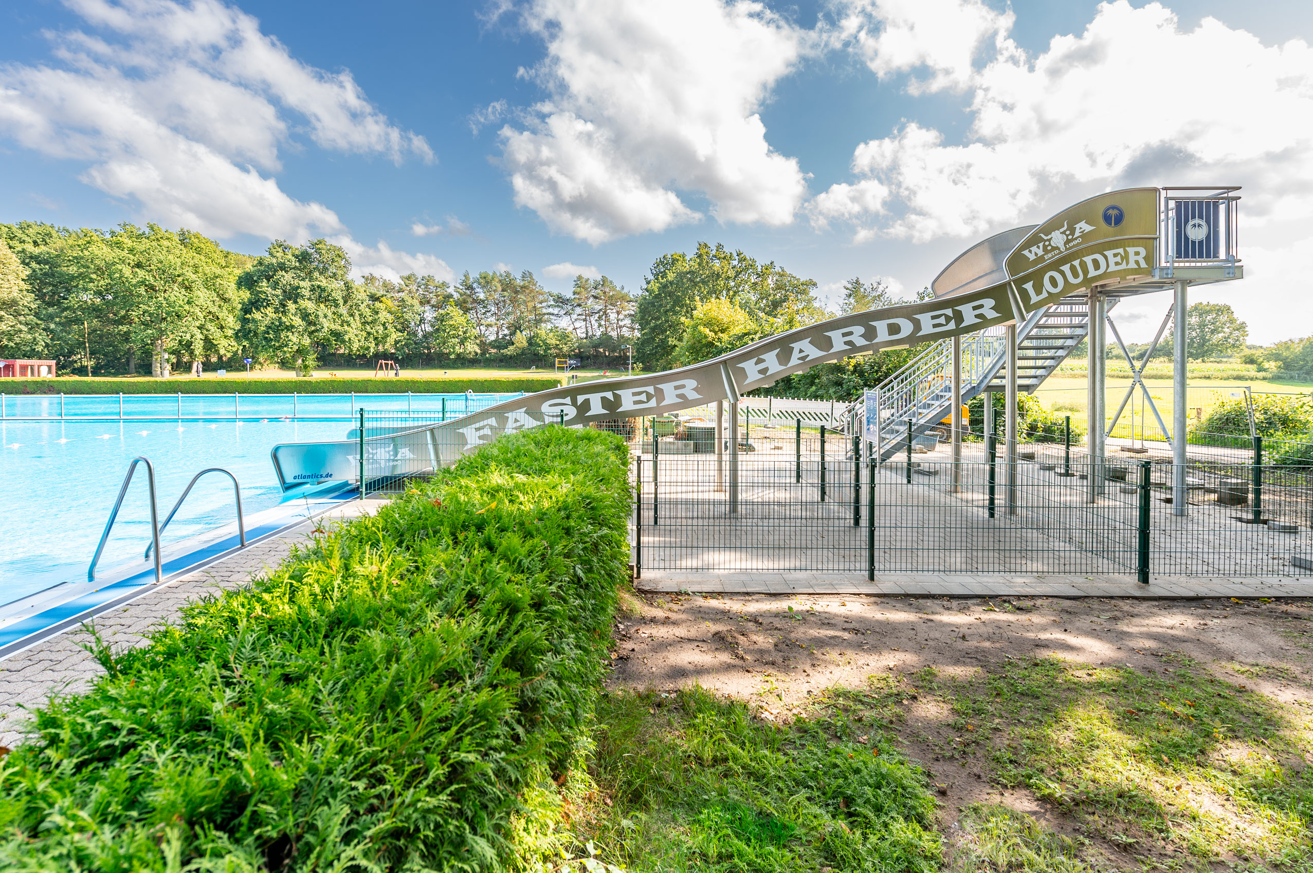 Breitwellenwasserrutsche aus Edelstahl im Freibad in Wacken, mit Aufschrift Faster Harder Louder für das Wacken Open Air
