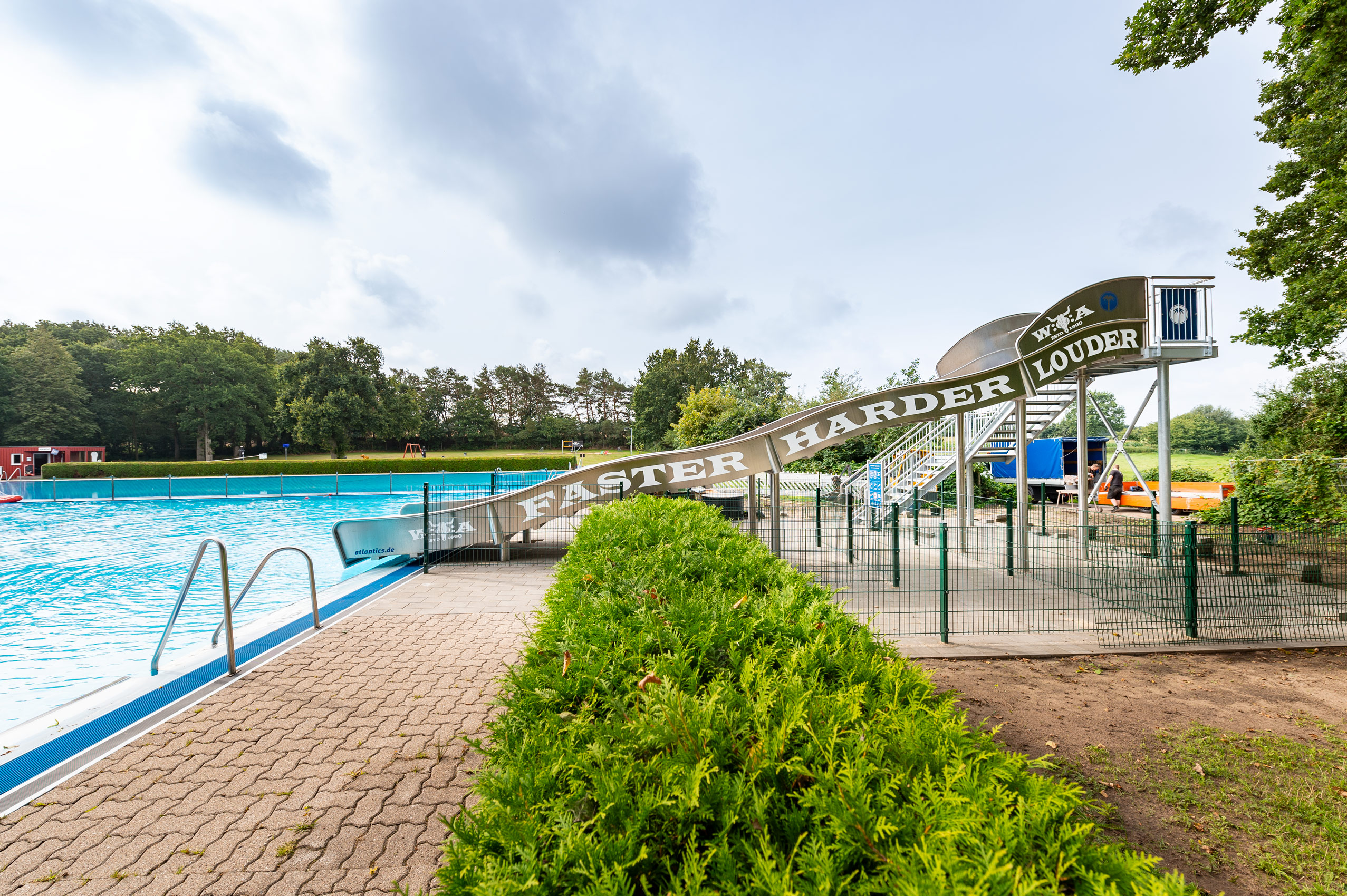 Breitwellenwasserrutsche aus Edelstahl im Freibad in Wacken, mit Aufschrift Faster Harder Louder für das Wacken Open Air
