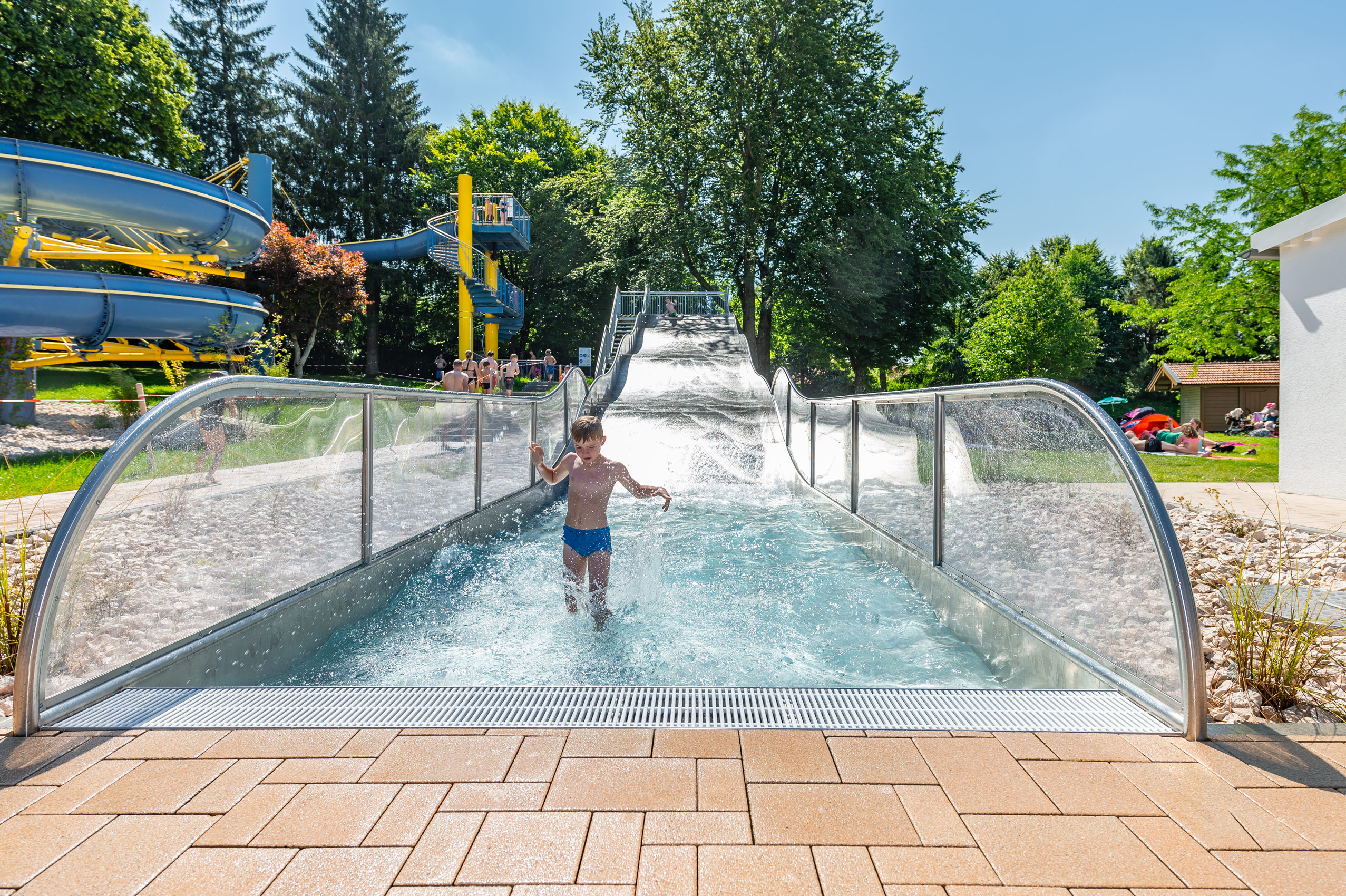 Kind tobt in der Breitwasserrutsche mit Landebecken im Franz-Haberlander-Freibad in Traunreut