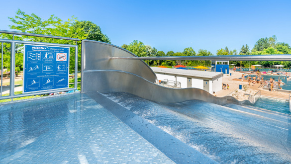 Blick von oben auf die Breitwasserrutsche mit Landebecken aus Edelstahl im Franz-Haberlander-Freibad in Traunreut