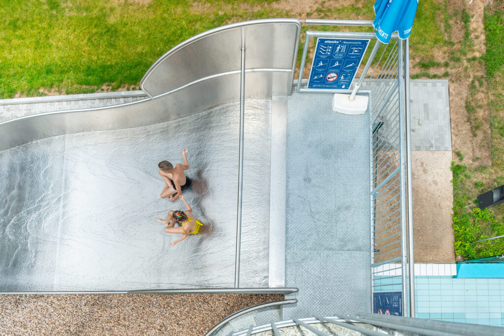 Vista de cima de crianças no Schätzlerbad em Weiden na Oberpfalz, a divertirem-se no escorrega aquático