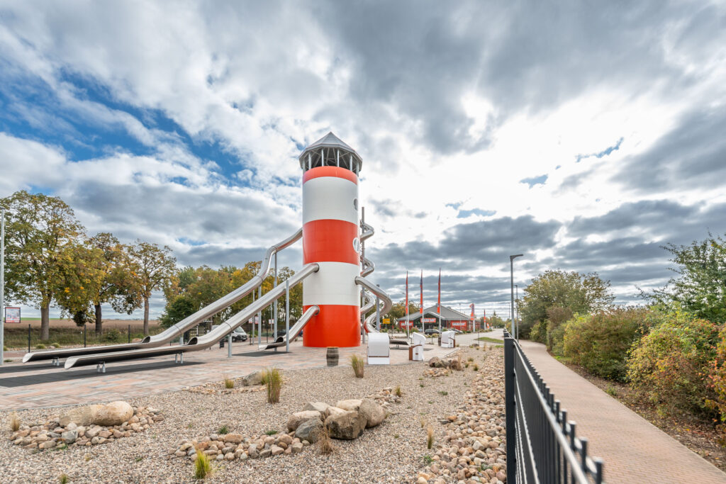atlantics Edelstahlrutschen Erlebnis Leuchtturm in rot-weiß als Spielplatz, Kaufhaus Stolz in Rechlin und sein Rutschenturm
