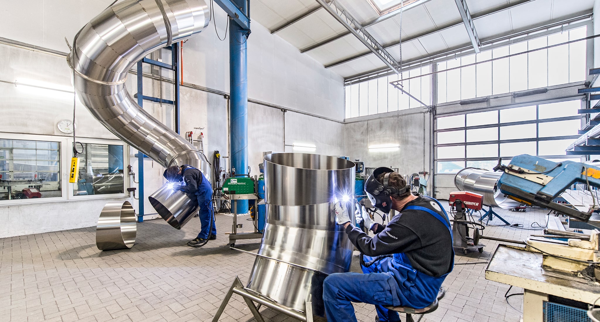 Zwei Mitarbeiter der atlantics GmbH bauen die Einzelteile der Edelstahlrutschen zusammen.