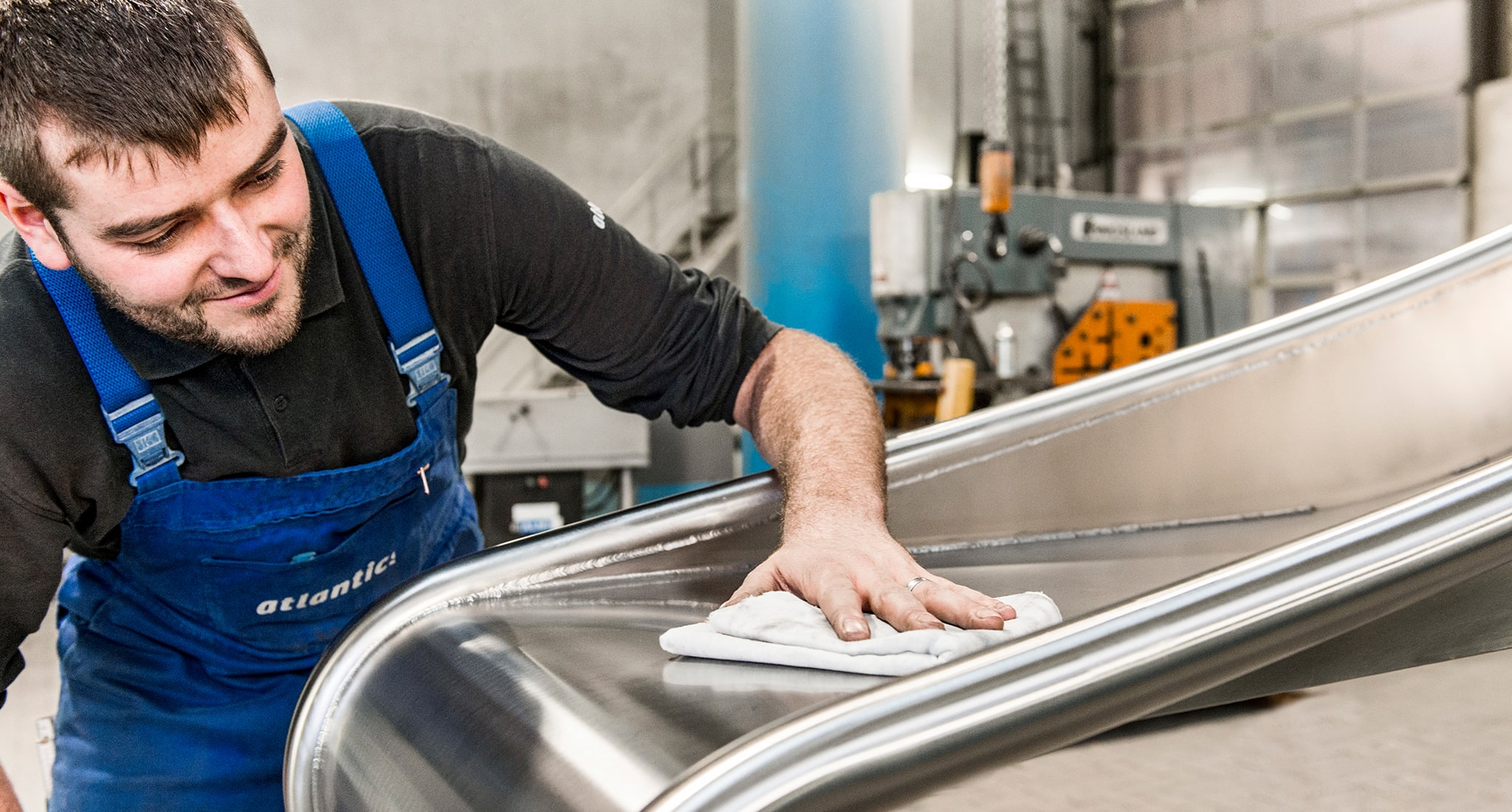 Ein Mitarbeiter der atlantics GmbH poliert die Fläche der Edelstahlrutschen.