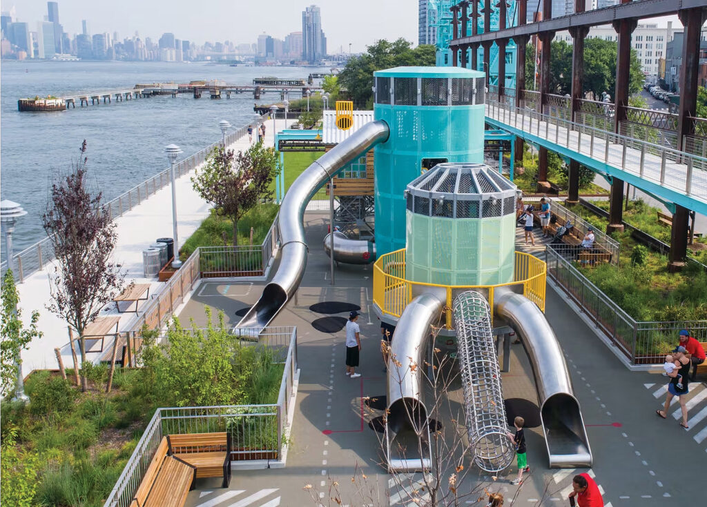 atlantics rostfria rutschkanor vid en lekstruktur på en lekplats i Brooklyn vid East River, New York City, USA