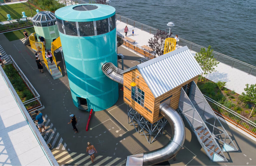 atlantics rostfria rutschkanor på en lekstruktur på en lekplats i Brooklyn vid East River, New York City, USA